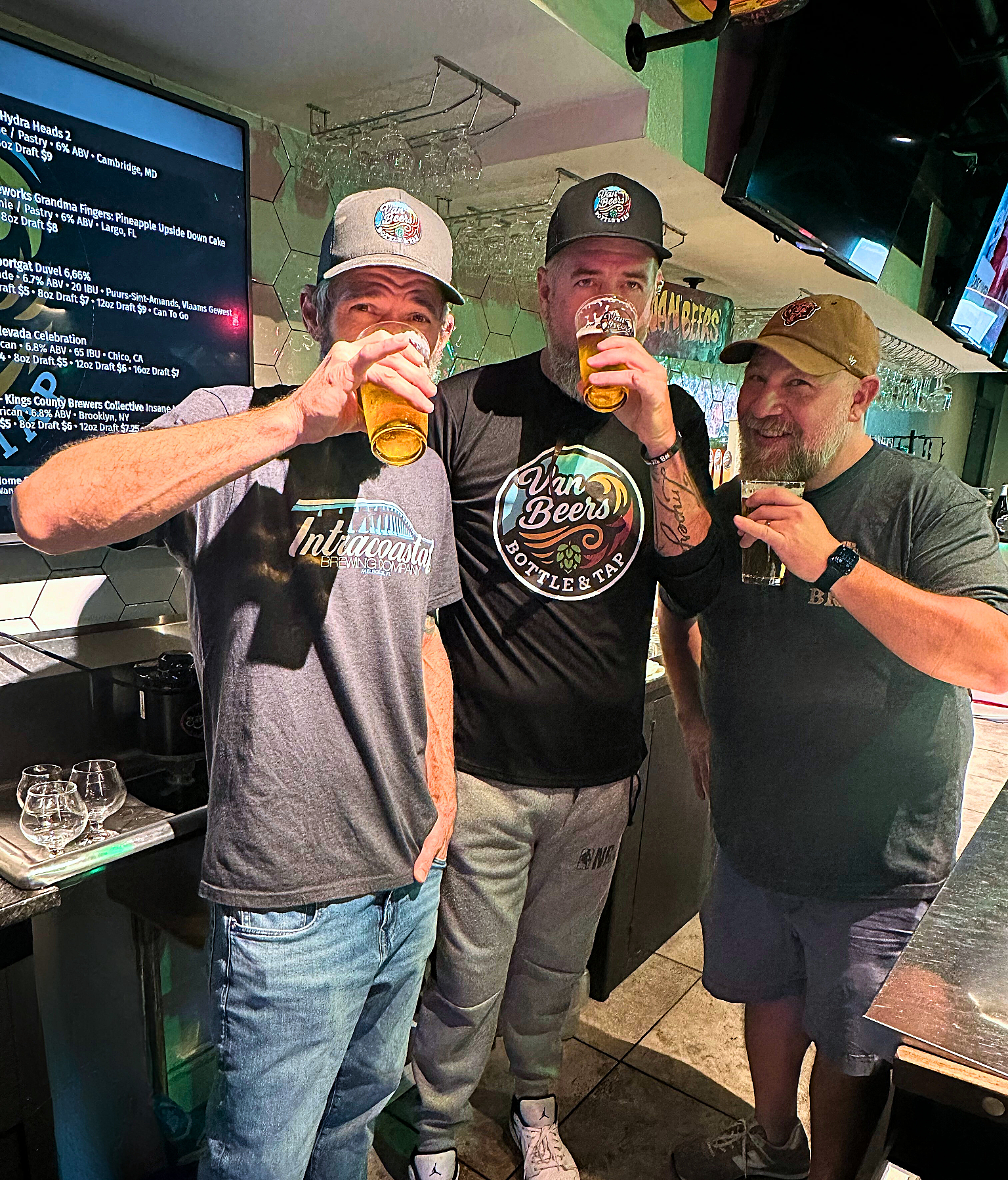 Van Beers Bottle & Tap founders Jay, Glenn, and Travis enjoying craft beer together behind the bar in their Melbourne FL taproom